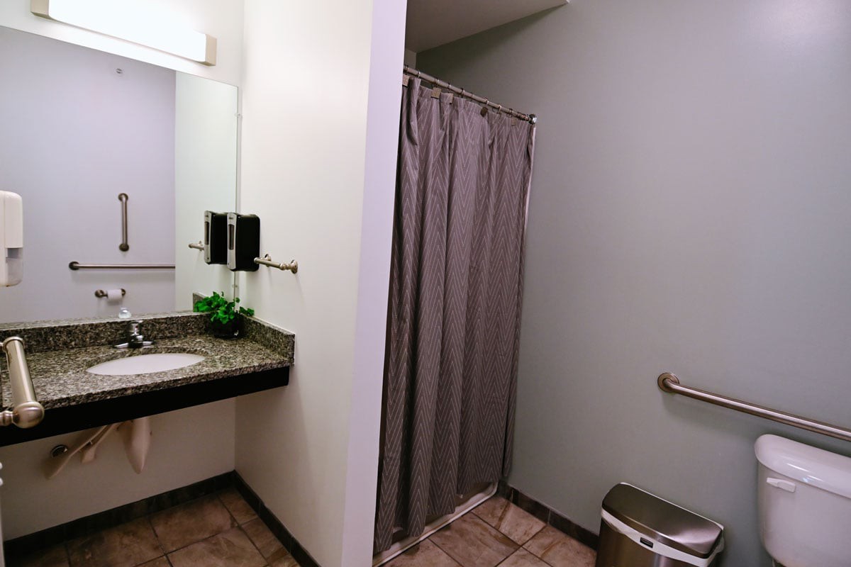 A modern bathroom featuring a sink, shower with a curtain, and a toilet.