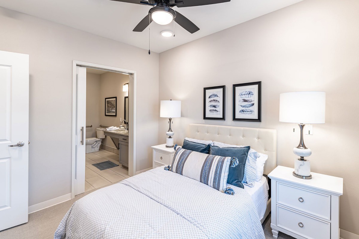 A modern bedroom with elegant decor, featuring a neatly made bed, stylish lamps, and framed wall art.