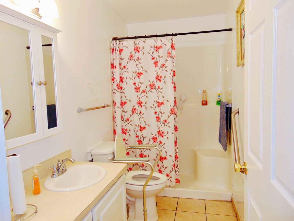 A bright bathroom featuring a floral shower curtain and neatly arranged fixtures.