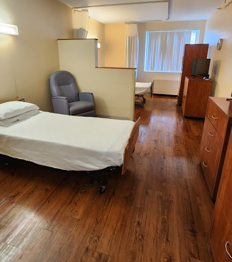 A well-lit hospital room featuring a single bed and comfortable seating.