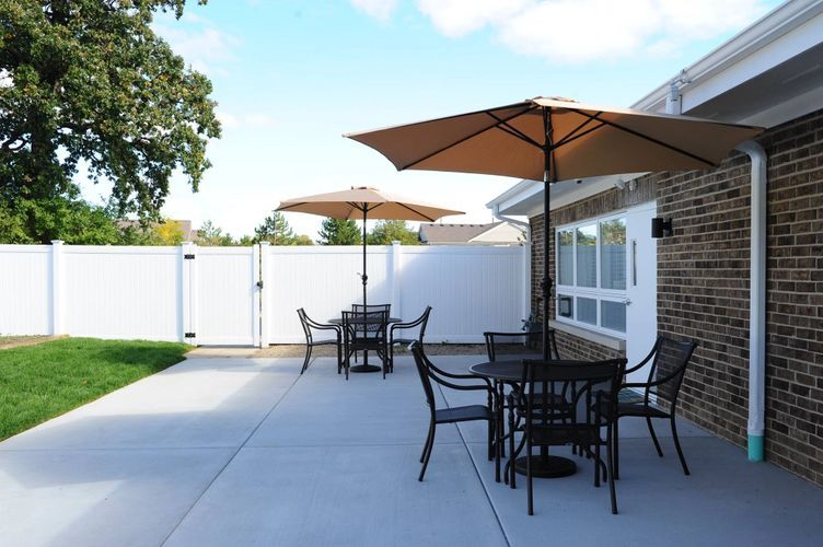 A sunny backyard patio with tables and chairs under large umbrellas.