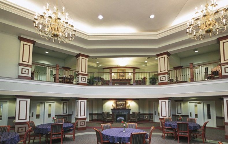 A spacious lobby with a chandelier, balconies, and dining tables.