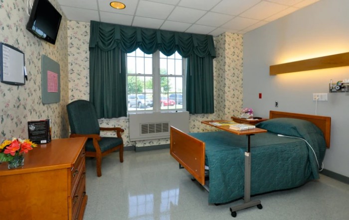 A clean and organized hospital room with a bed, chair, and window.