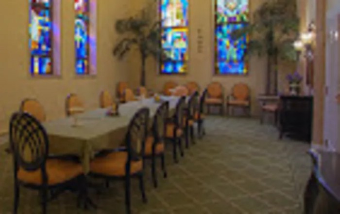 A dining room with stained glass windows and arranged chairs around tables.