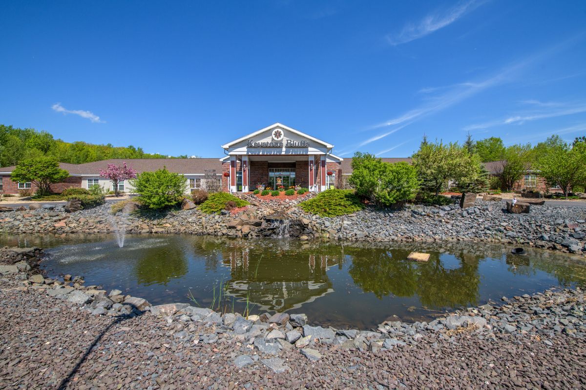 A scenic landscape with a pond in front of a building under a clear blue sky.