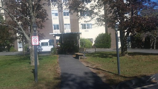 A view of a residential building with a pathway surrounded by grass and trees.