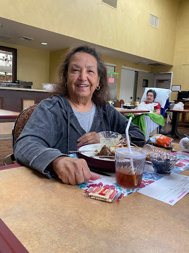 A cheerful woman enjoying a meal and drink in a cozy dining area.