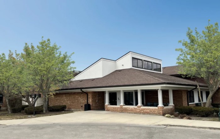 A suburban building with a modern architectural design, surrounded by trees on a clear day.