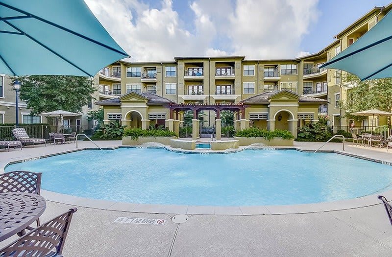 A luxurious apartment complex with a large outdoor swimming pool.