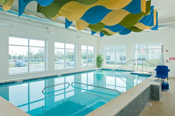 A bright indoor swimming pool with modern decor and large glass windows.