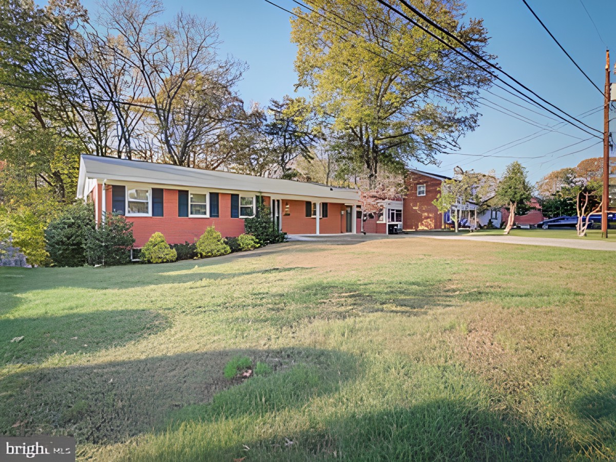 A suburban home with a spacious front lawn and surrounding trees on a sunny day.
