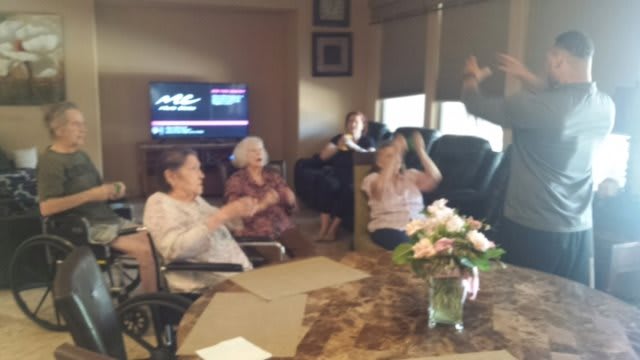 A group of people enjoying a celebration in a living room with flowers on the table.