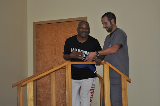 A healthcare professional assists a patient in walking during rehabilitation, showcasing support and progress.