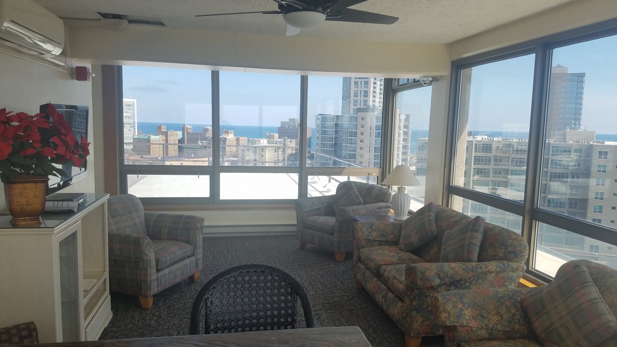 A cozy living room with large windows offering a cityscape and ocean view.