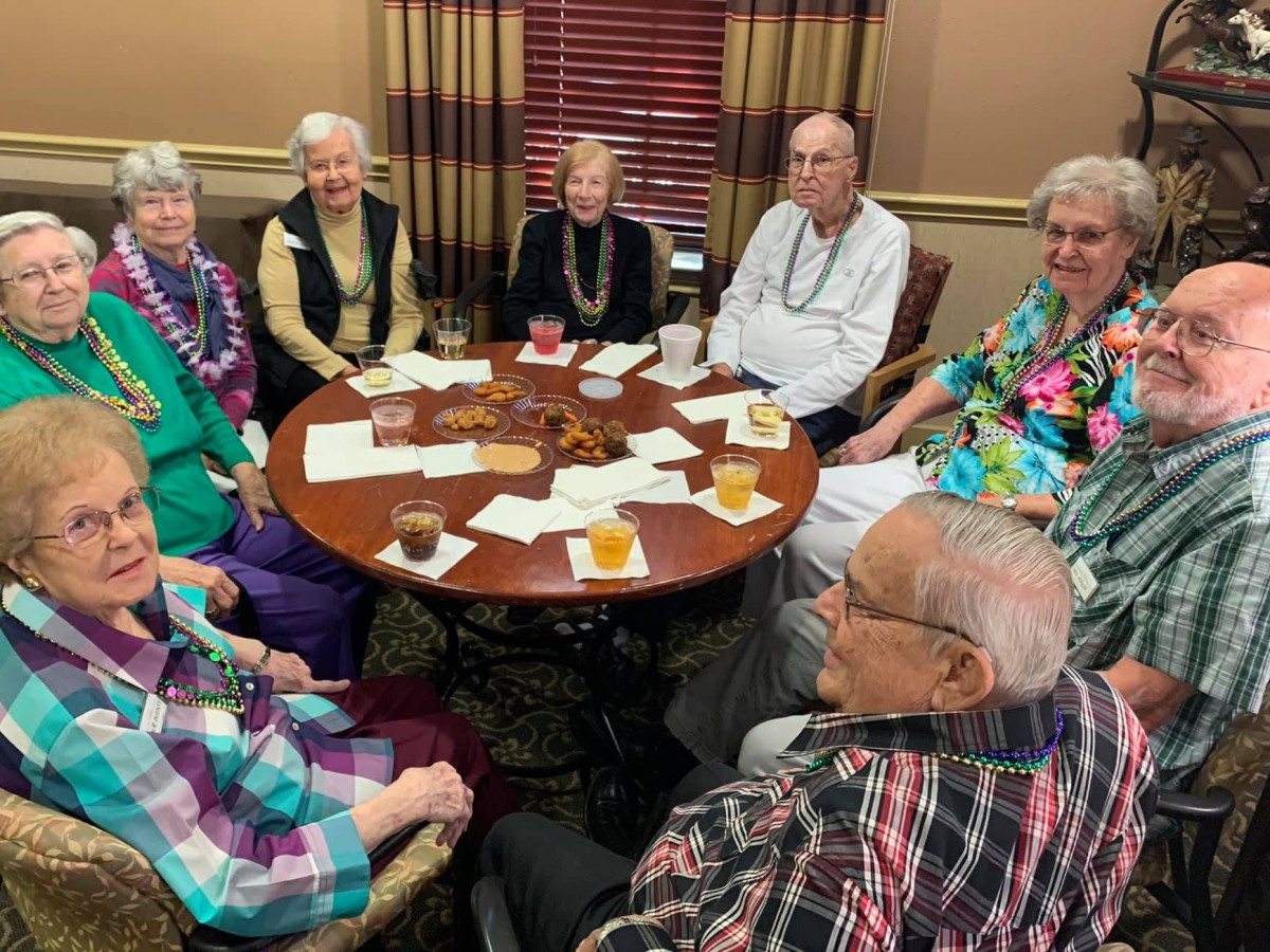 A group of seniors socializing around a table indoors.
