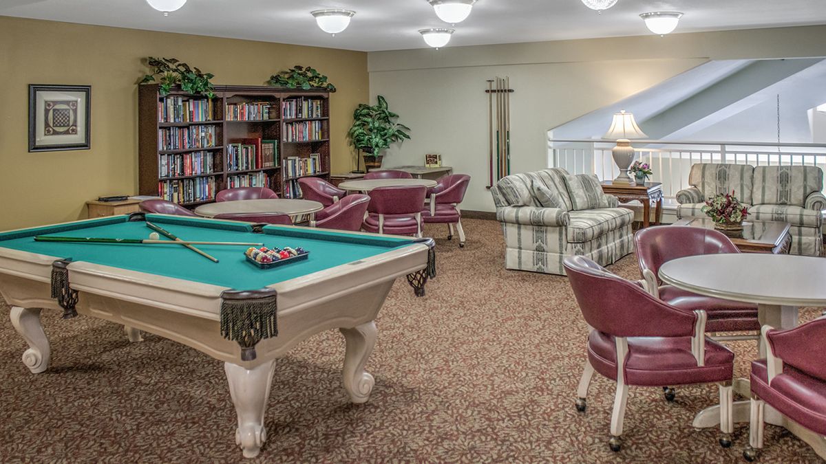 A cozy recreational room featuring a pool table, bookshelves, and comfortable seating areas.
