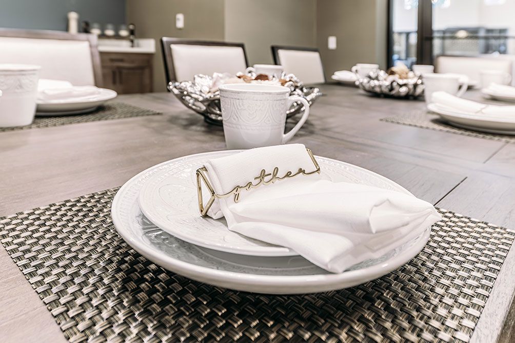 An elegantly set dining table with plates, a napkin, and a name card holder beside a mug.