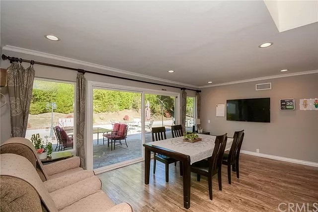A modern dining room featuring a table set with chairs, wood flooring, and large sliding glass doors opening to an outdoor area.