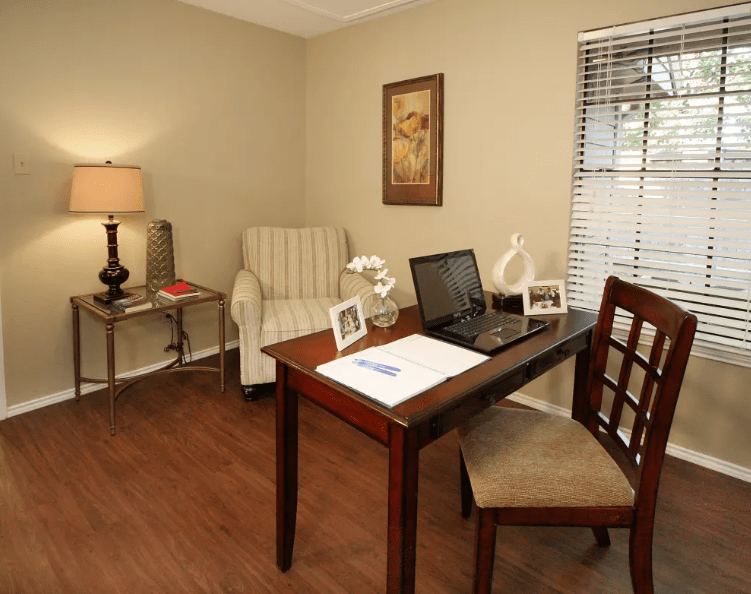 A cozy home office with a desk, chair, and laptop by the window.