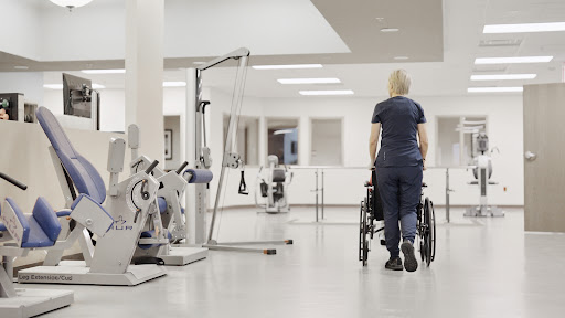 A healthcare professional guiding a wheelchair in a rehabilitation center.