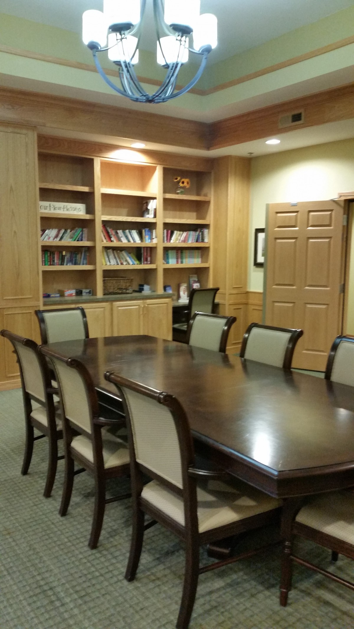 A conference room with a large table, surrounded by chairs and bookshelves.
