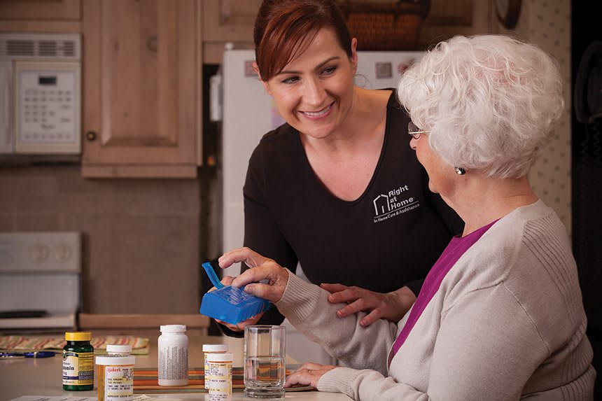 A caregiver assists an elderly woman with her medication at home.