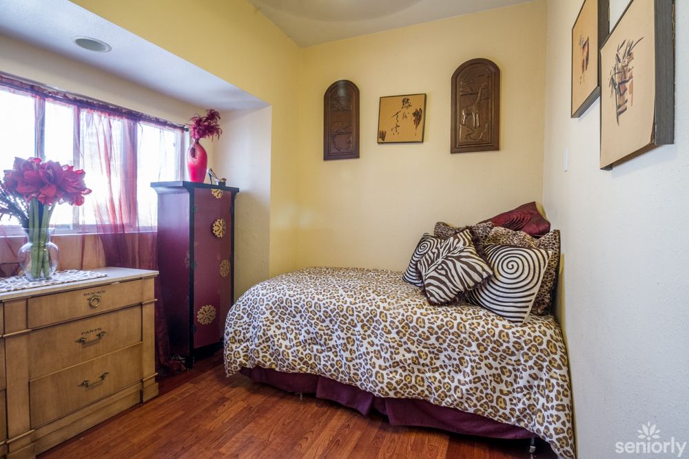 A cozy bedroom with stylish decor, featuring a bed adorned with patterned pillows and a wooden floor.