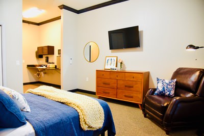 A cozy and modern bedroom interior with a bed, dresser, and wall-mounted TV.