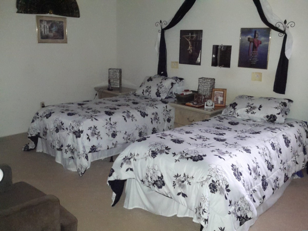 A cozy bedroom featuring twin beds with matching floral bedding and stylish wall decor.