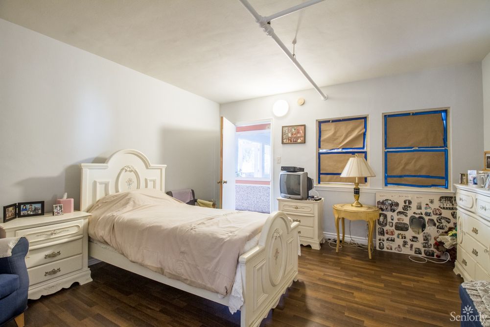 A neatly organized bedroom with a bed, nightstand, lamp, and television.