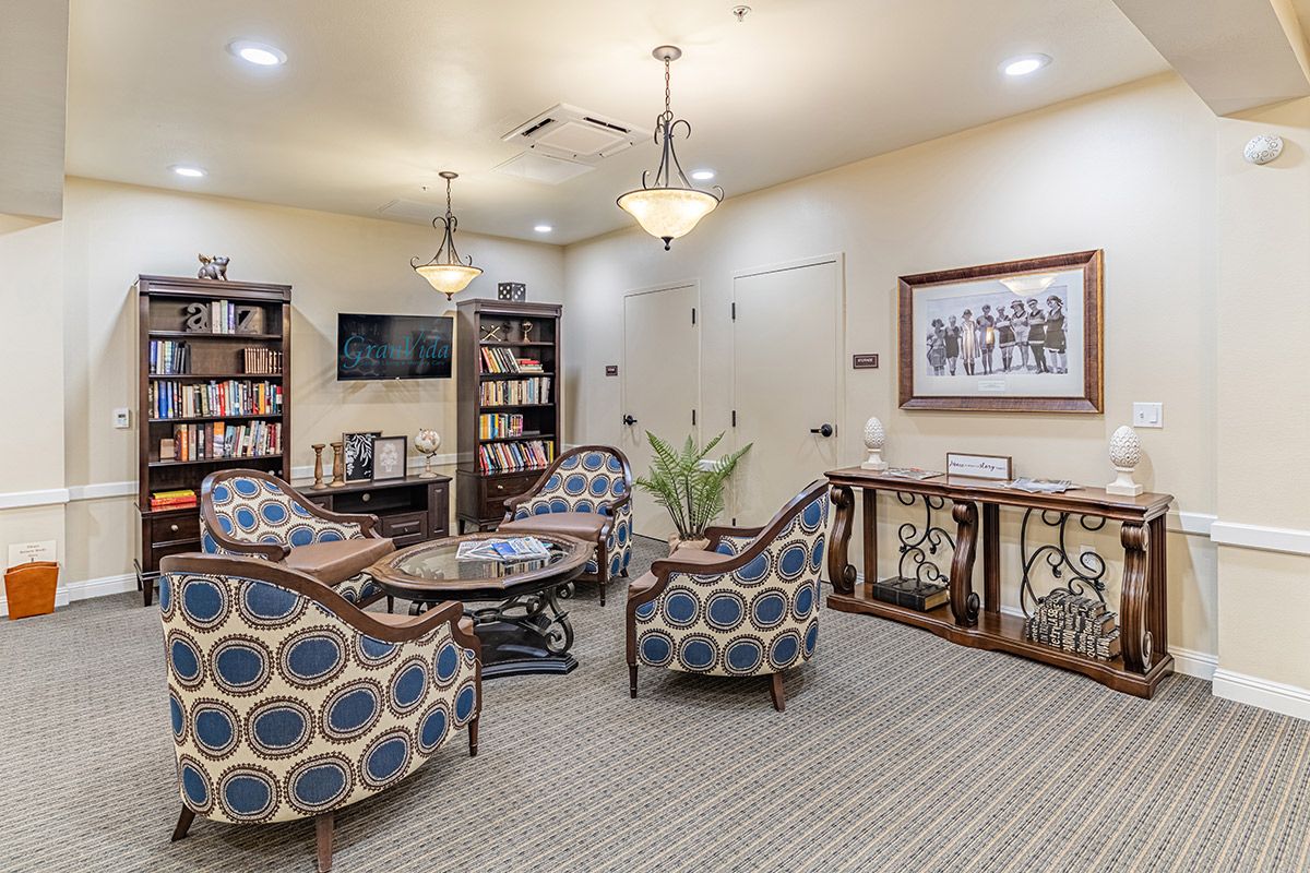 A cozy living room with patterned chairs, a television, and bookshelves.