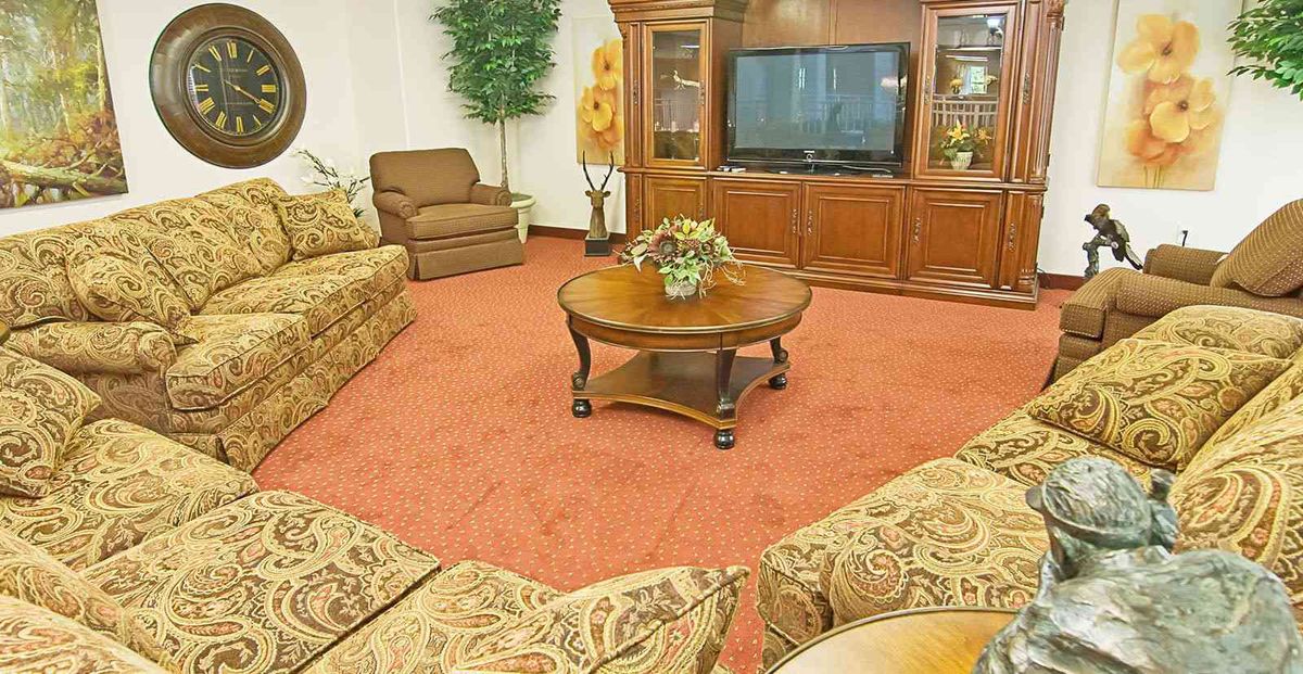 A cozy living room with patterned sofas, a wooden coffee table, and a large TV.