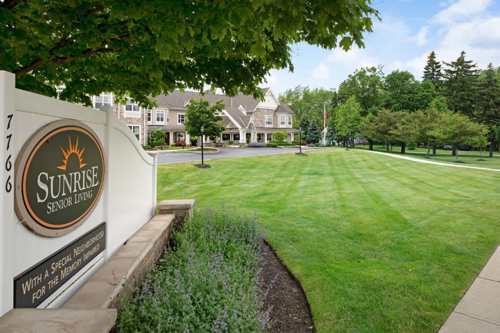 A well-maintained lawn leads to a large building with a prominent sign.