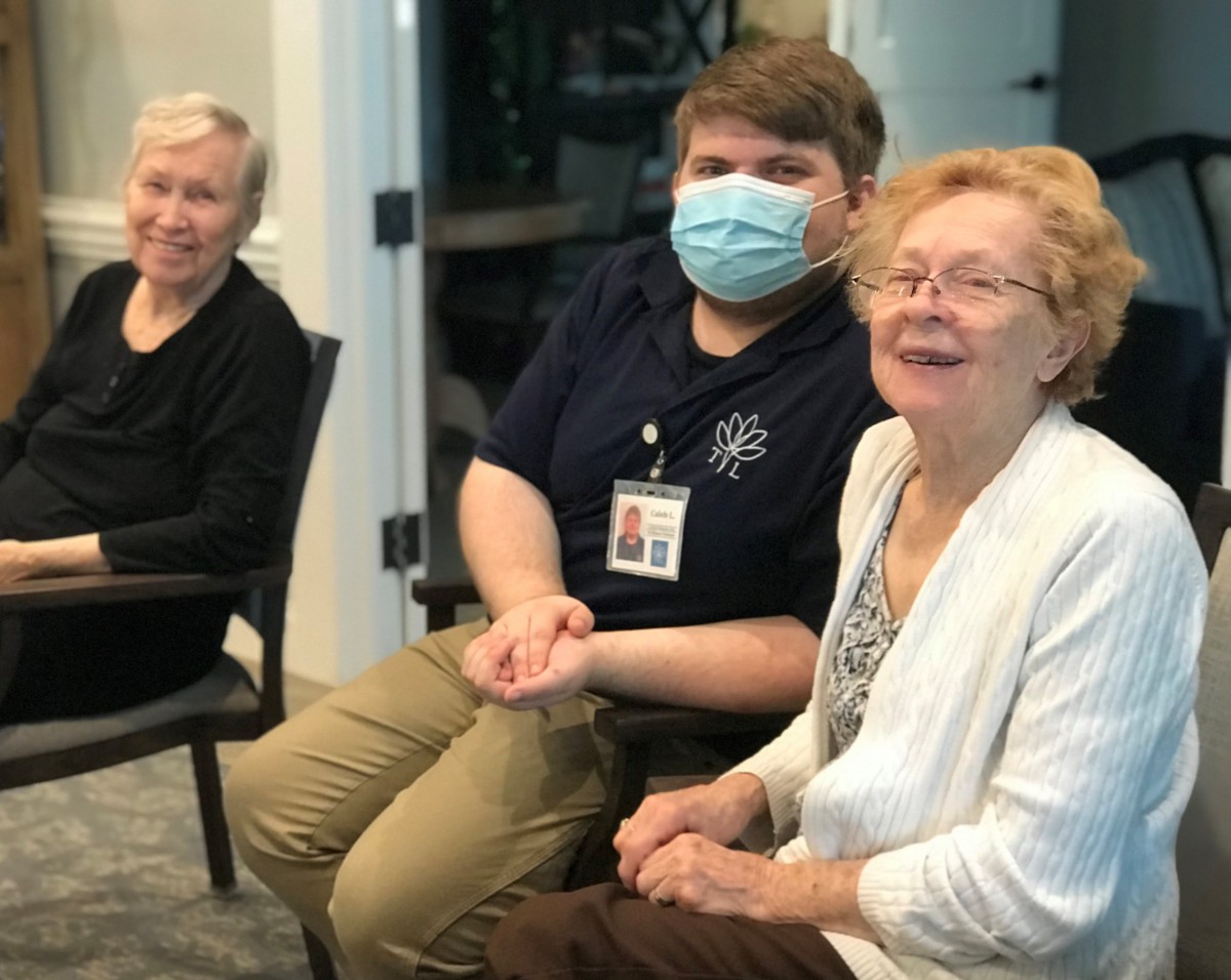 A caregiver interacts with elderly individuals in a community setting.