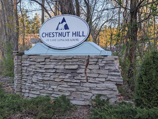 A welcoming sign for Chestnut Hill, surrounded by natural greenery.