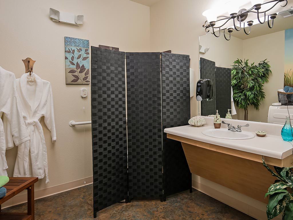 A bathroom with a sink, mirror, and decorative screen.