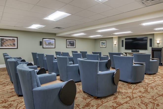 A small theater room with blue chairs and a large screen.