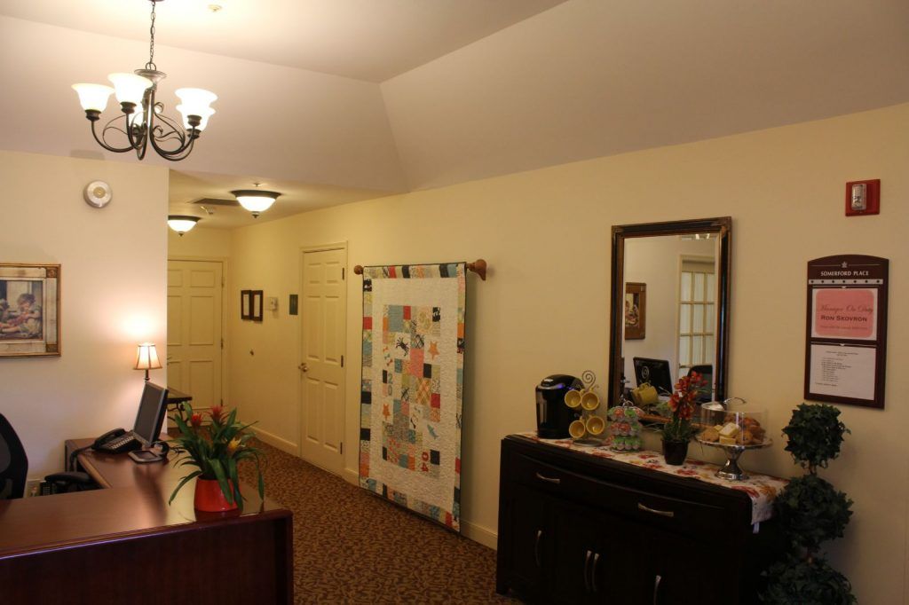 A cozy hallway interior with a decorative quilt, mirror, and furniture.