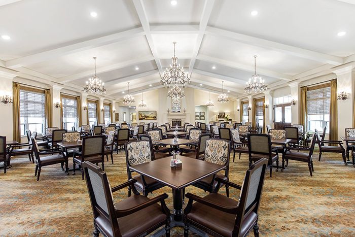 An elegantly designed dining room featuring chandeliers and neatly arranged tables and chairs.