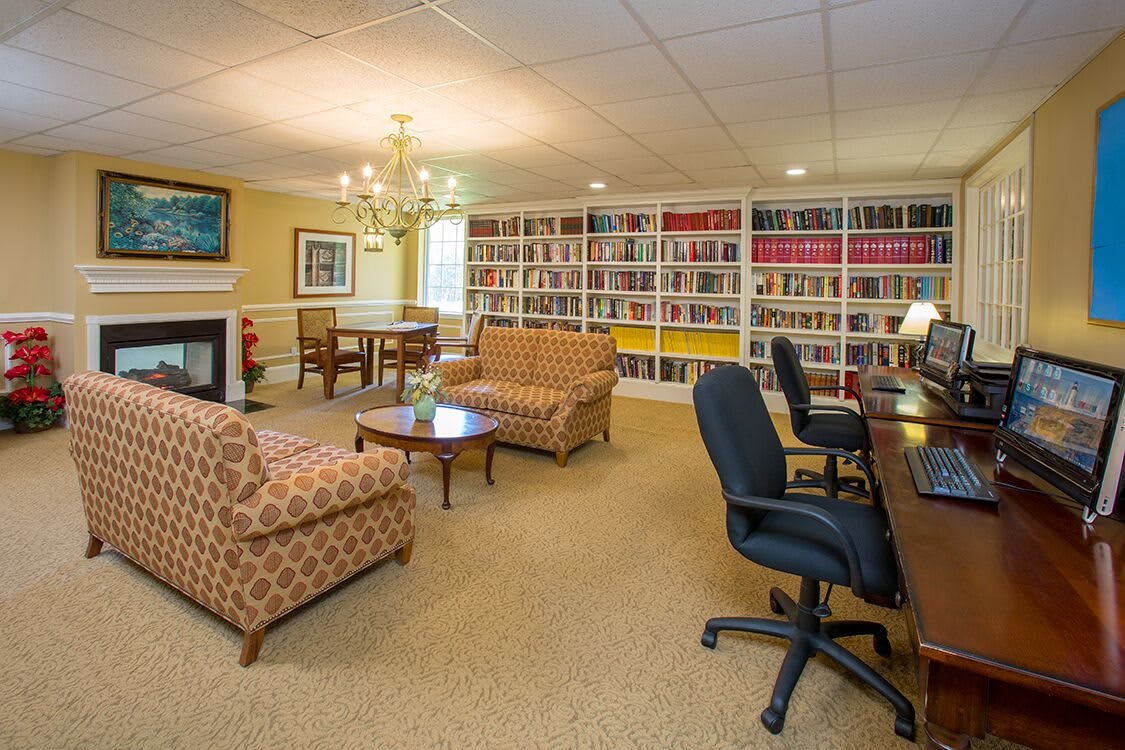 A cozy library lounge with bookshelves, comfortable seating, and computer workstations.