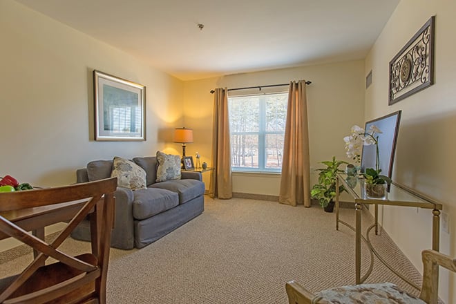 A cozy living room with a sofa, television, and natural lighting from the window.
