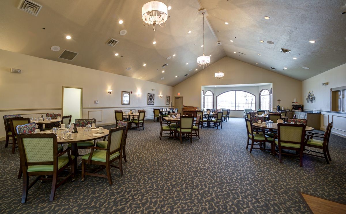 A spacious dining area with elegantly arranged tables and chandeliers.
