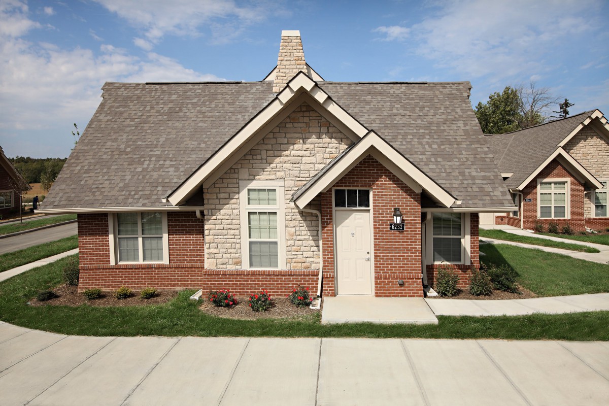 A suburban brick house with a gabled roof and a small front yard.