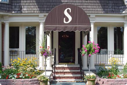 A welcoming entrance featuring a decorative awning and vibrant flowers.
