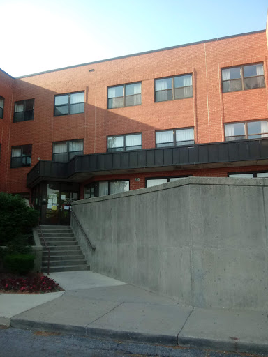 A brick building with multiple windows and a staircase leading to the entrance.