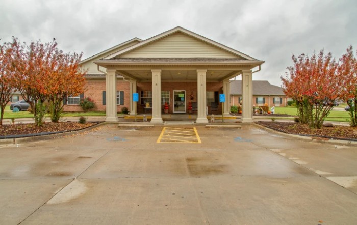 A building entrance with columns and a driveway on a cloudy day.