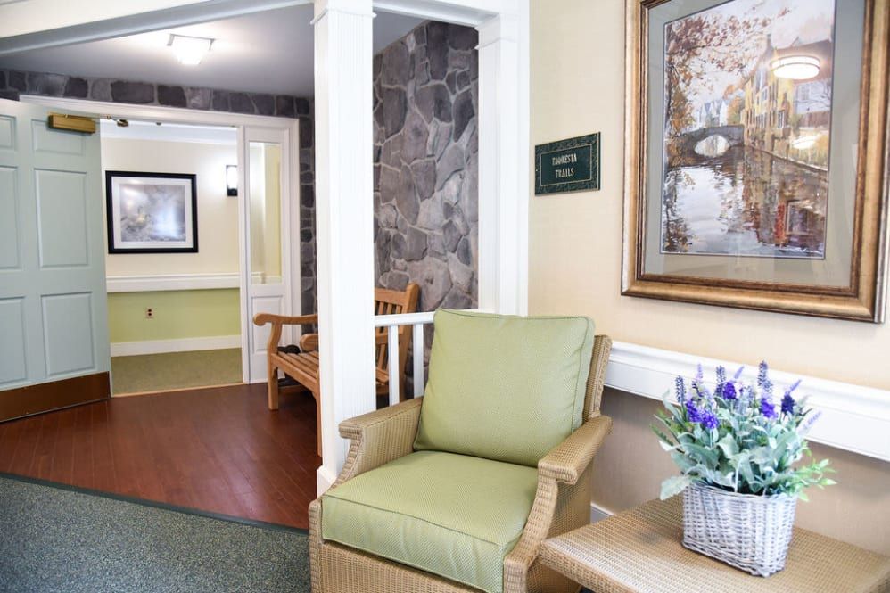 A cozy lobby area with a green chair and artwork on the wall.
