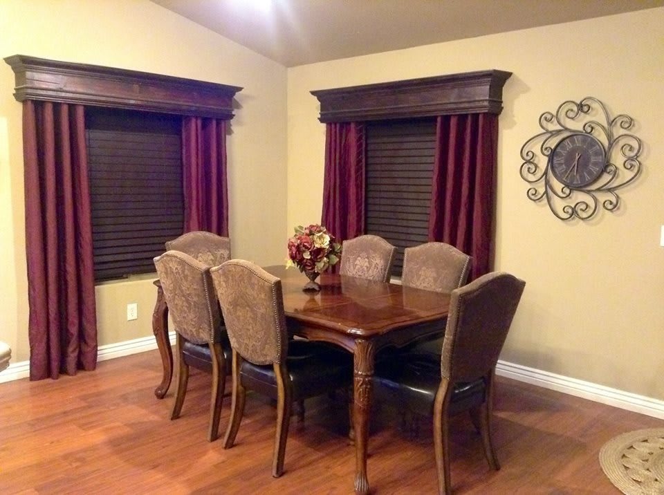 A cozy dining room with a wooden table set and elegant curtains.