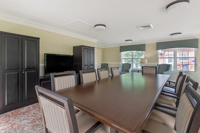 A spacious conference room with a large meeting table, chairs, and a television.