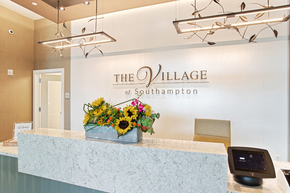 A modern reception desk at The Village of Southampton, adorned with a vibrant arrangement of flowers.